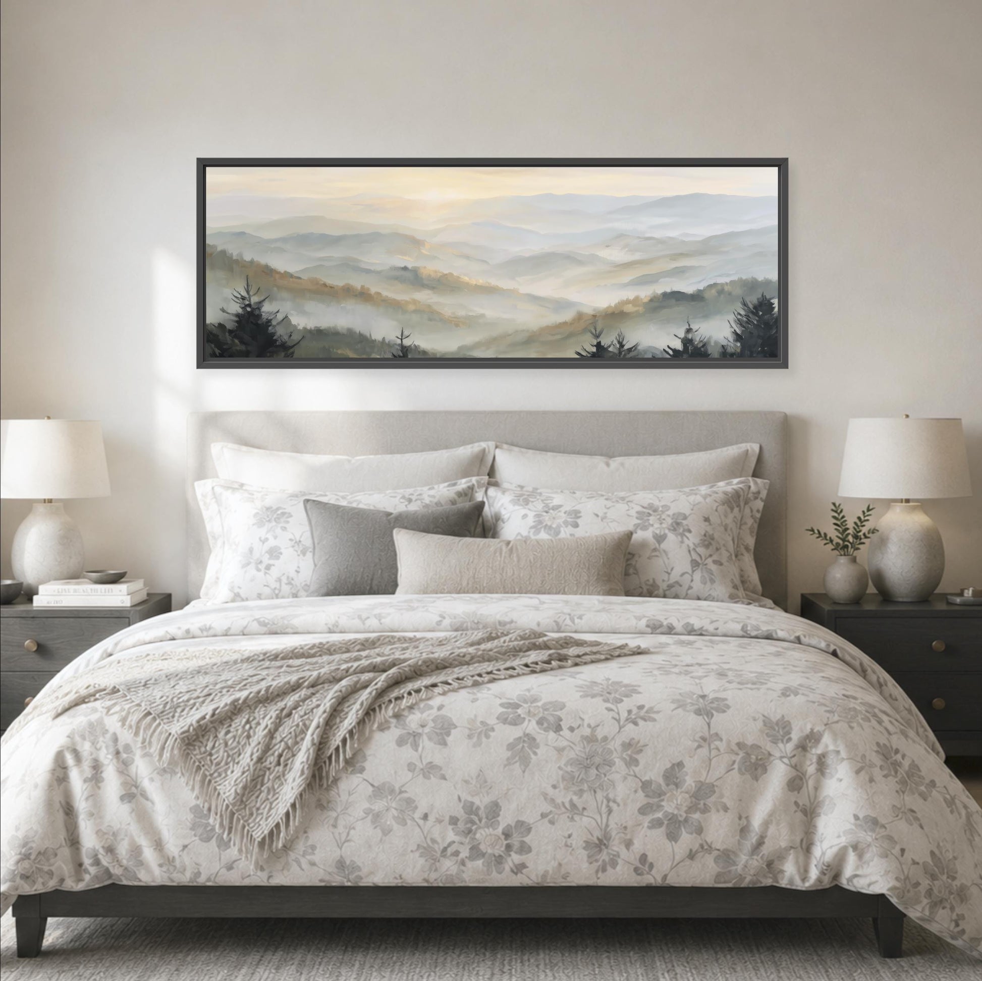 a large bed with a floral bedspread and pillows, flanked by two nightstands with lamps. Above the bed is a large framed landscape painting depicting a mountain range with a hazy, misty atmosphere.