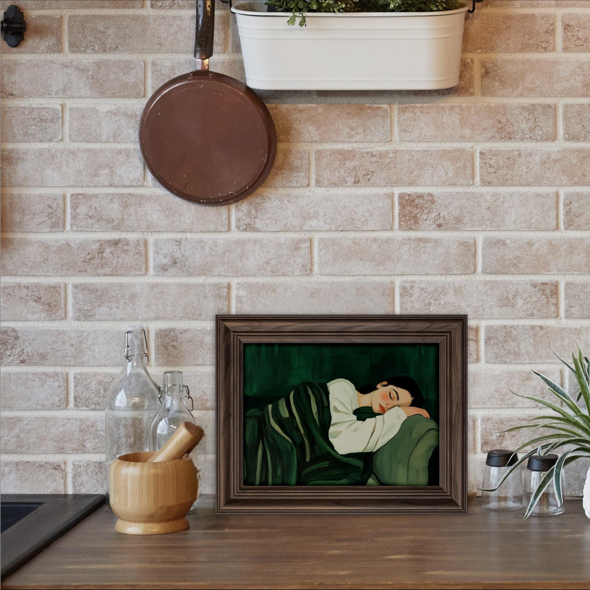 a framed painting of a woman sleeping on a couch, placed on a wooden surface in a kitchen setting.