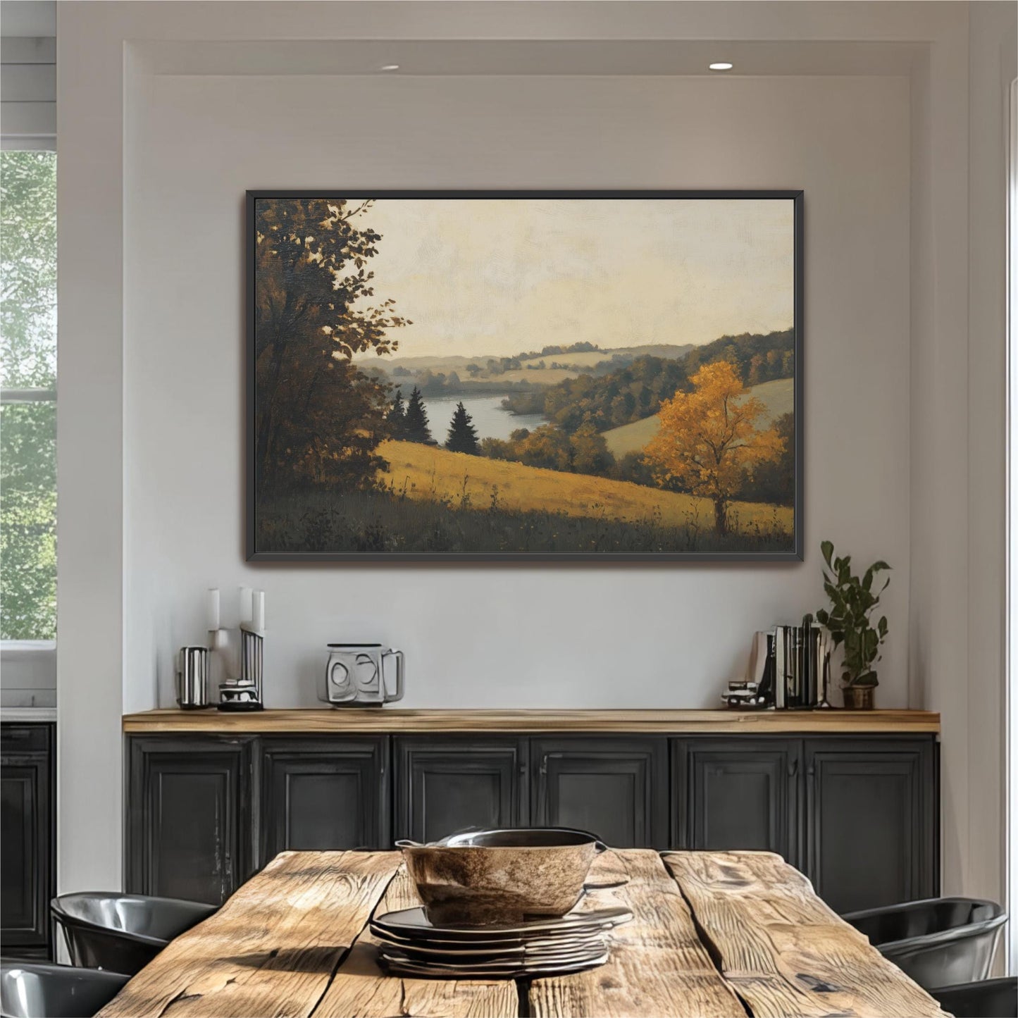 a large painting of a countryside landscape hanging on a wall above a wooden dining table. The table is set with plates and bowls, and there are some plants and decorative items on the table.