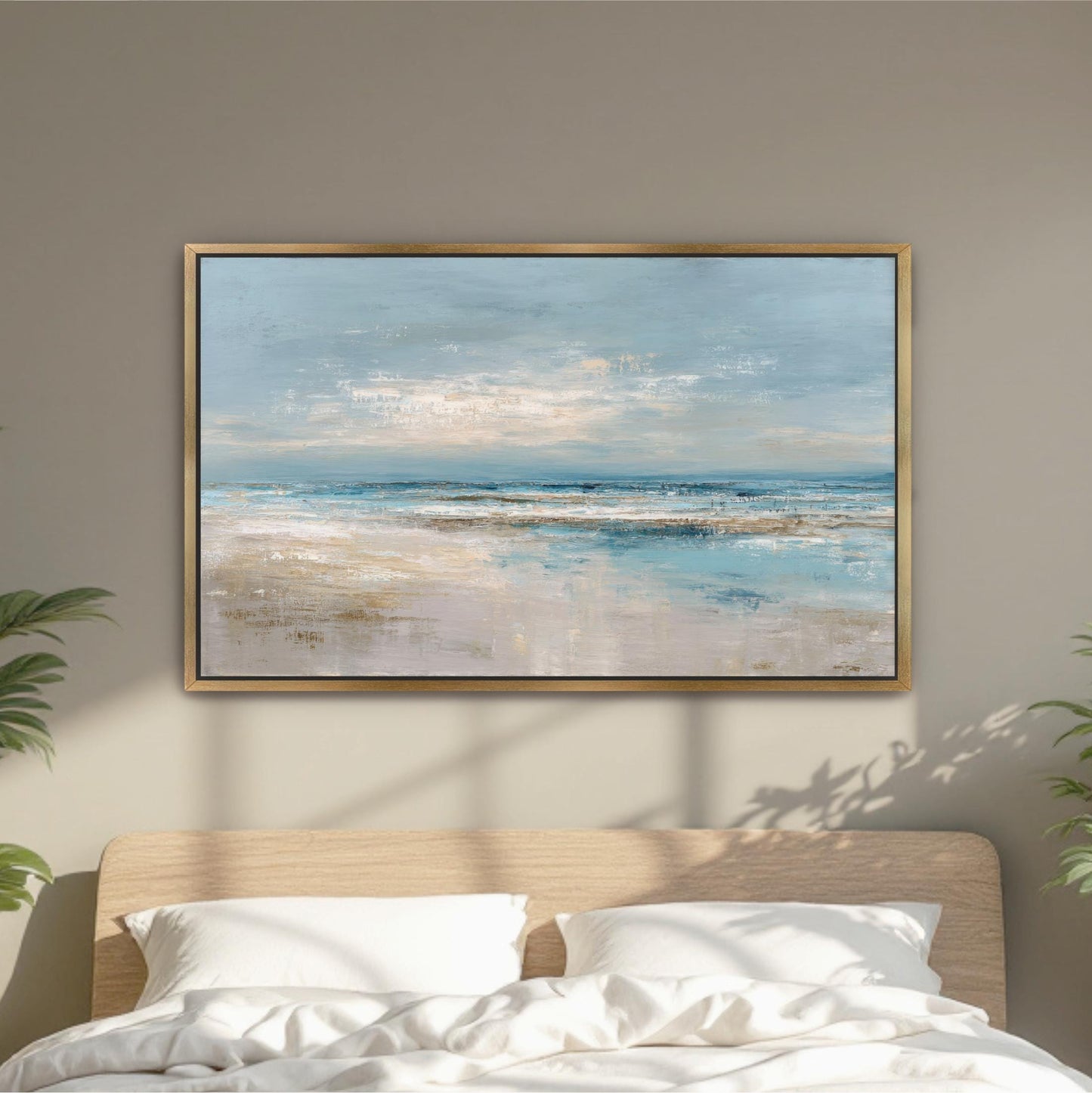 a large, framed painting of a serene beach scene hanging above a bed with white pillows.