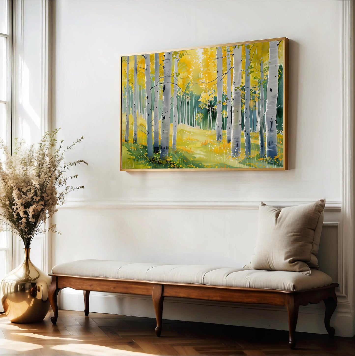 a large painting of a forest with yellow trees hanging on a white wall above a wooden bench with a beige cushion.