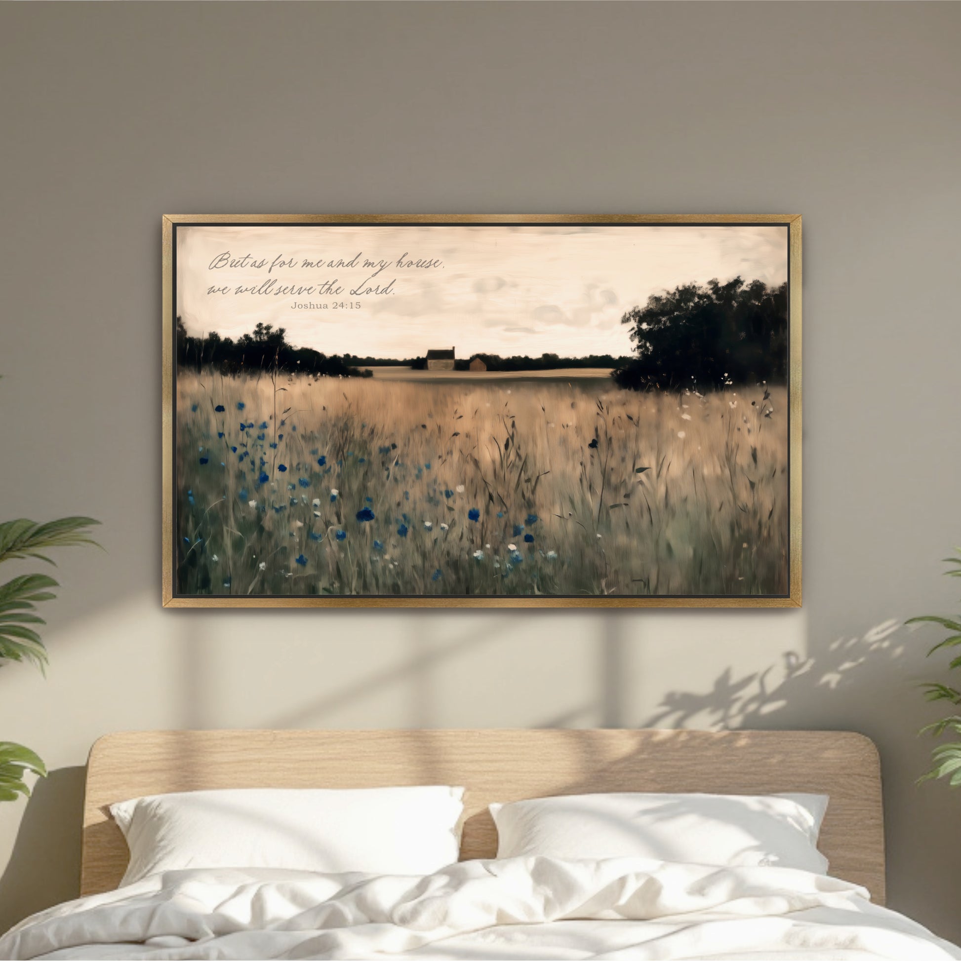 A framed painting of a field with tall grass and blue flowers hangs on a wall above a bed with white pillows.
