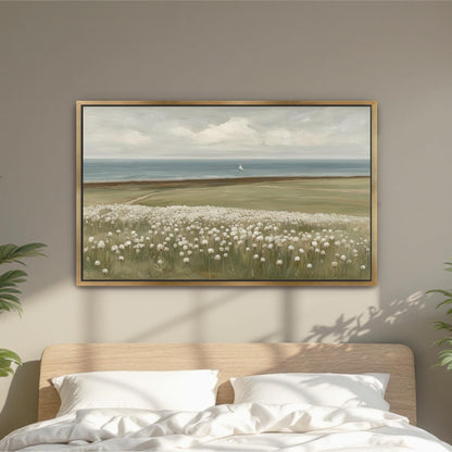 a large painting of a field with white flowers hanging on a wall above a bed with white pillows.