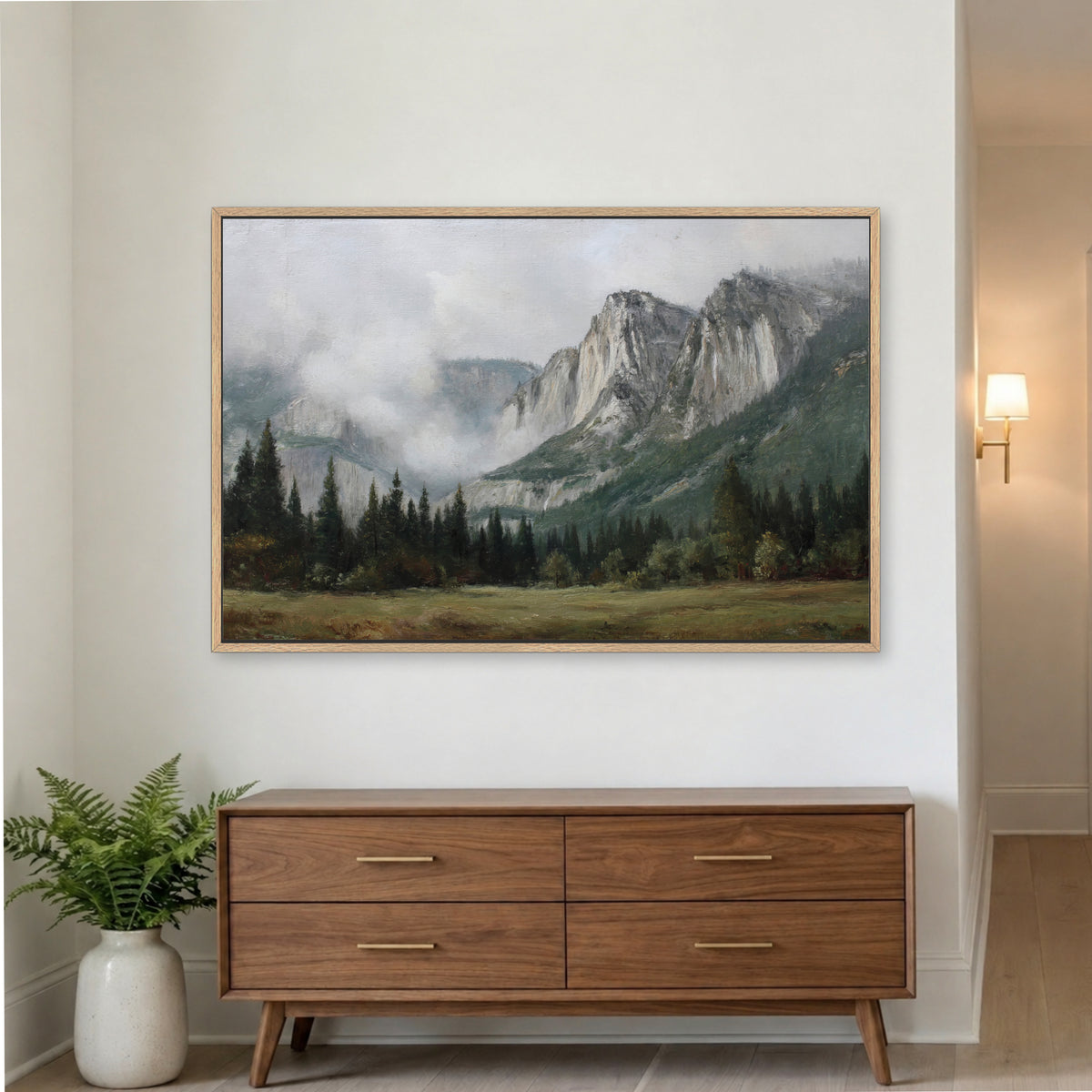 a large landscape painting hanging on a white wall above a wooden dresser with four drawers.