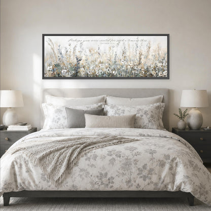 a large bed with a floral bedspread and pillows, flanked by two nightstands with lamps. Above the bed is a framed artwork depicting a field of flowers.