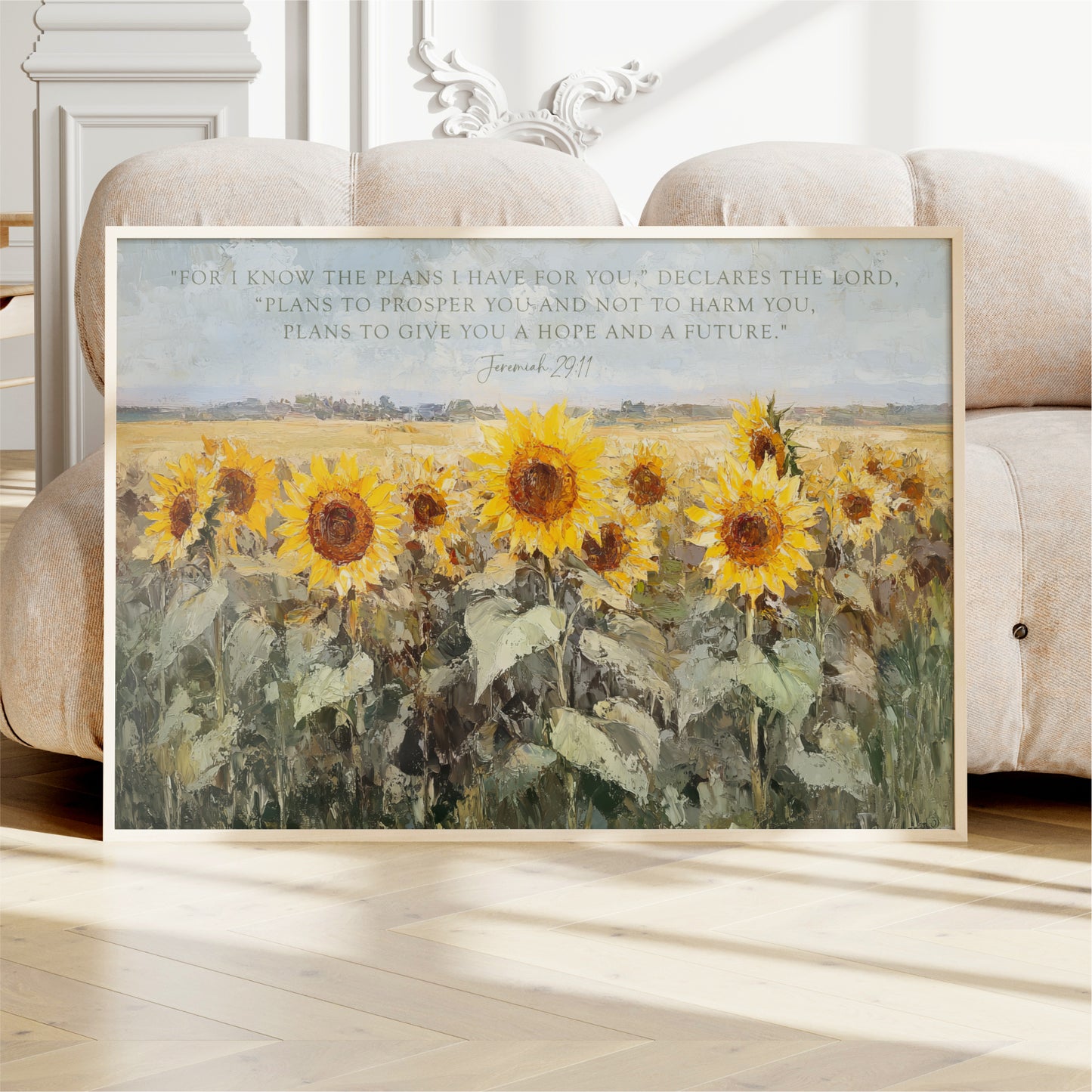 A framed painting of a field of sunflowers is displayed on a white couch in a room.
