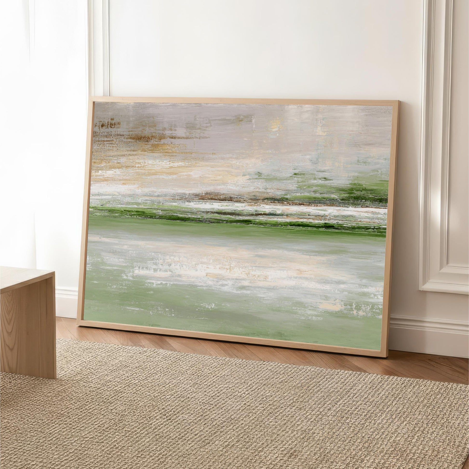 a large abstract painting with a predominantly green and white color palette, displayed on a wooden floor against a white wall.