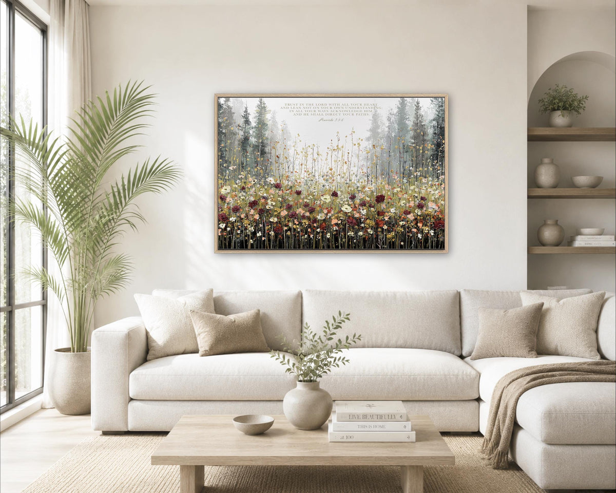 a cozy living room with a large white sofa, a wooden coffee table, and a framed painting of a forest scene hanging on the wall above the sofa.