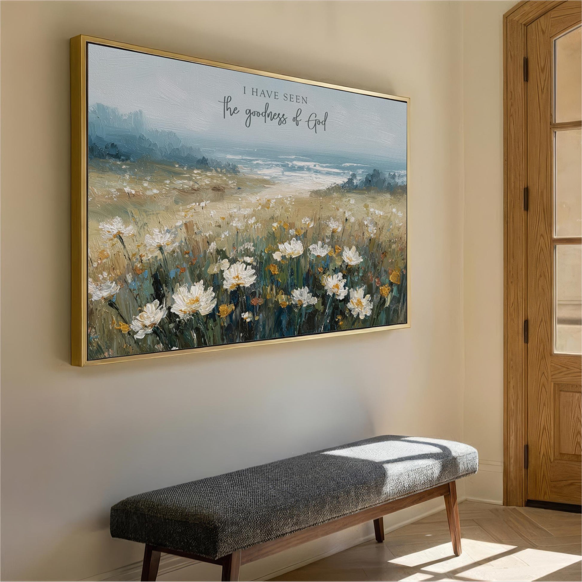 a large painting of a field of flowers hanging on a wall, with a bench in front of it.