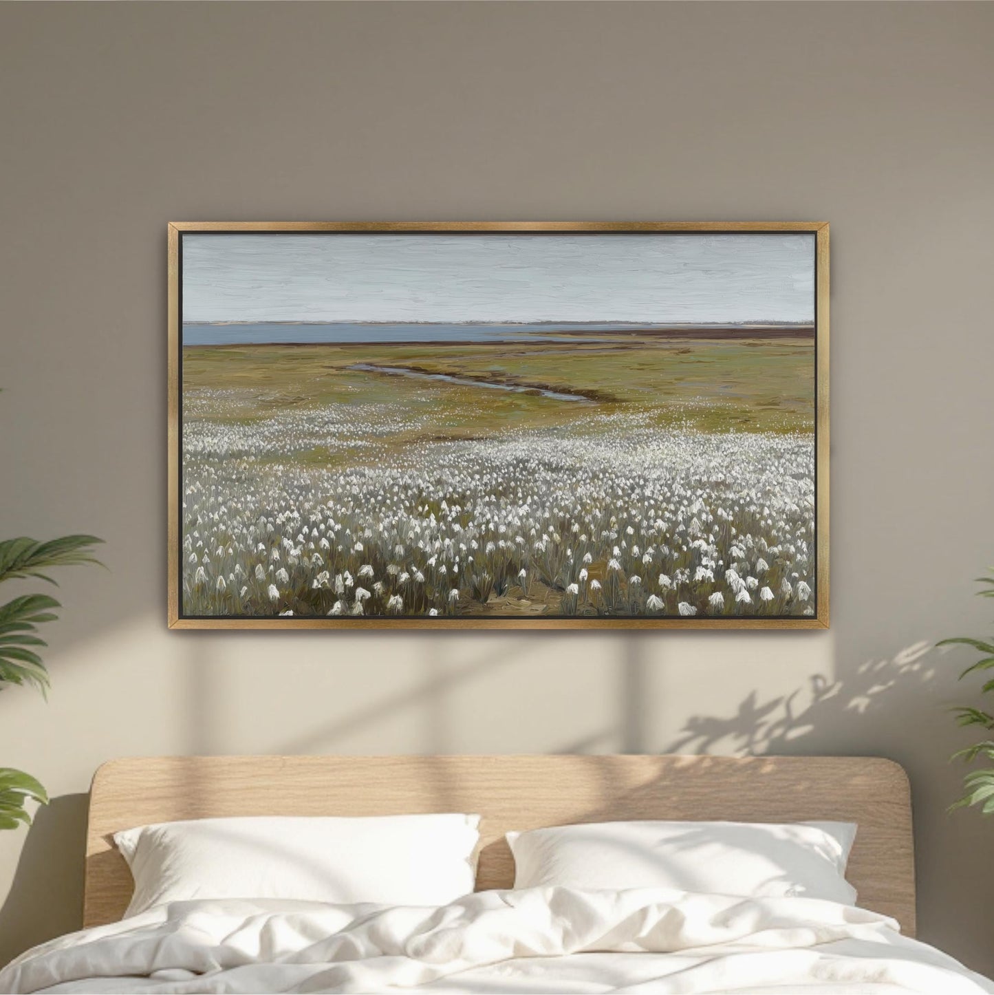 a large painting of a field with white flowers hanging on a wall above a bed with white pillows.