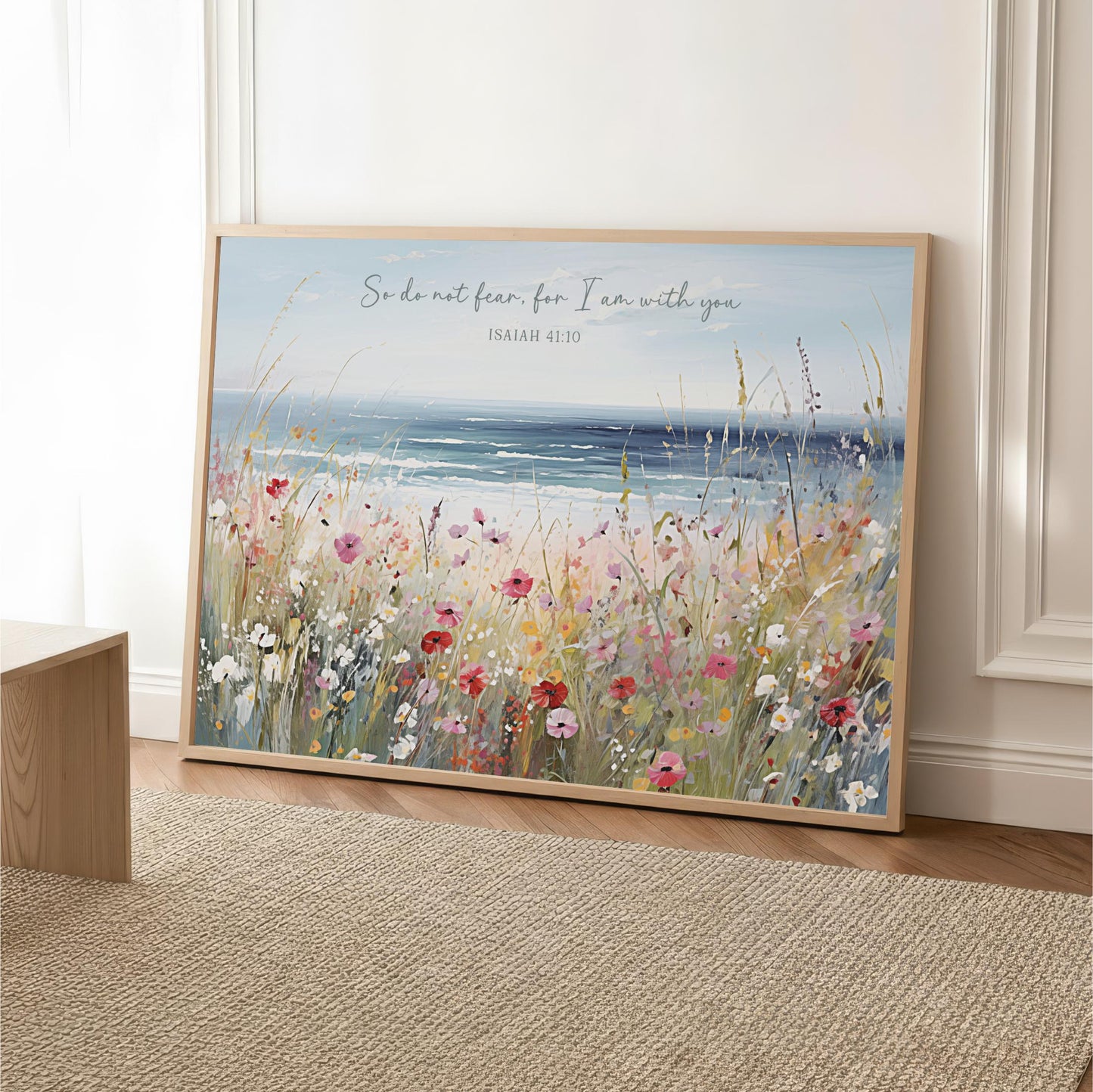 A framed painting depicting a serene landscape with a field of colorful flowers and a body of water in the background.