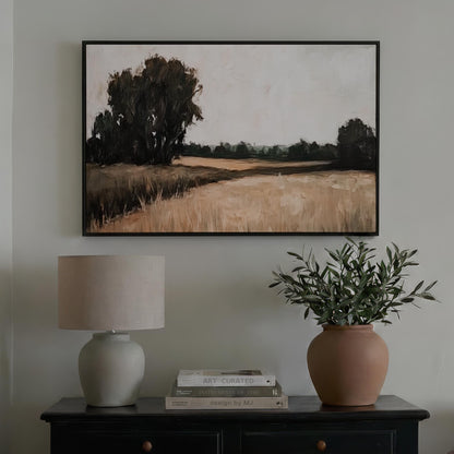 a black dresser with a lamp, a potted plant, and a framed landscape painting hanging on the wall above it.