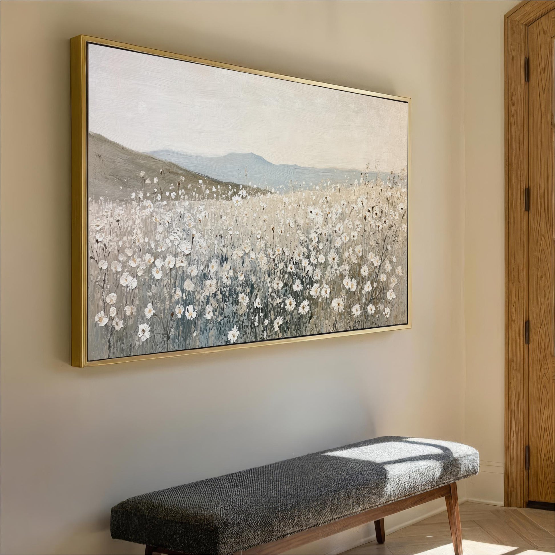 a large painting of a field of flowers hanging on a wall, with a bench placed below it.