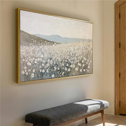 a large painting of a field of flowers hanging on a wall, with a bench placed below it.