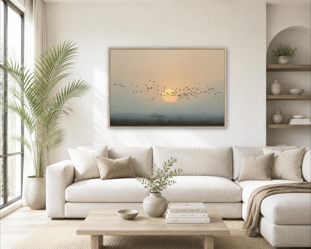 a serene living room with a large window, a white sofa, a wooden coffee table, and a framed painting of a sunrise over a landscape.