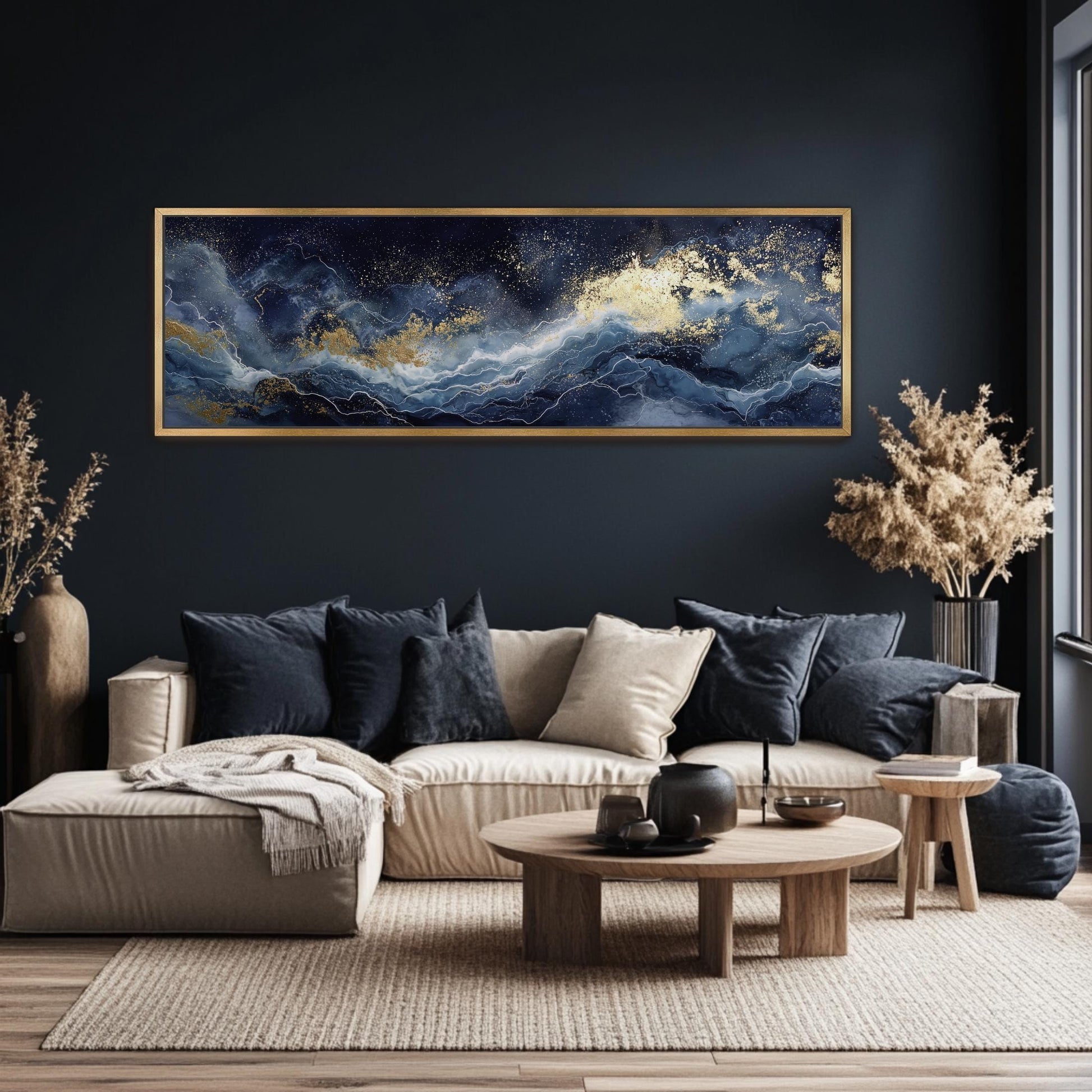 a modern living room with a large, dark blue abstract painting hanging on the wall above a beige sofa. The sofa is adorned with throw pillows and a wooden coffee table. The room also features a large window, a side table, and a potted plant, creating a cozy and stylish atmosphere.