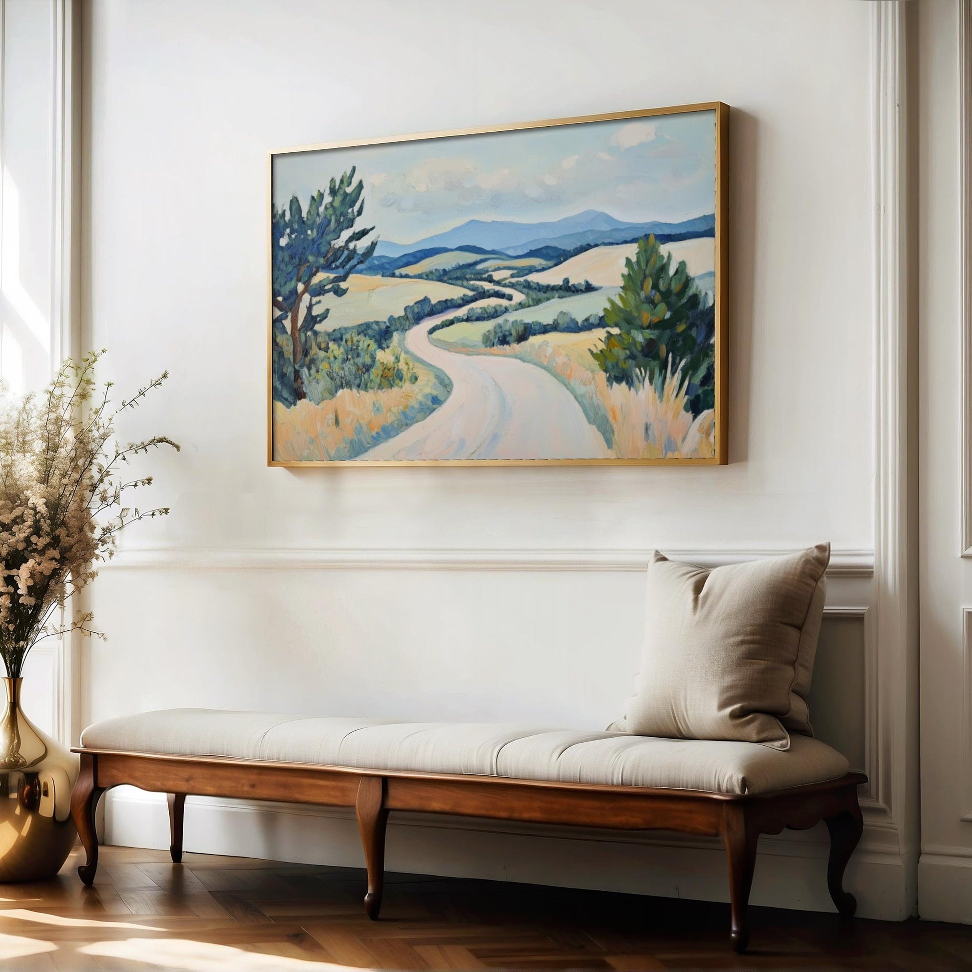 a large landscape painting hanging on a white wall above a wooden bench with a beige cushion.
