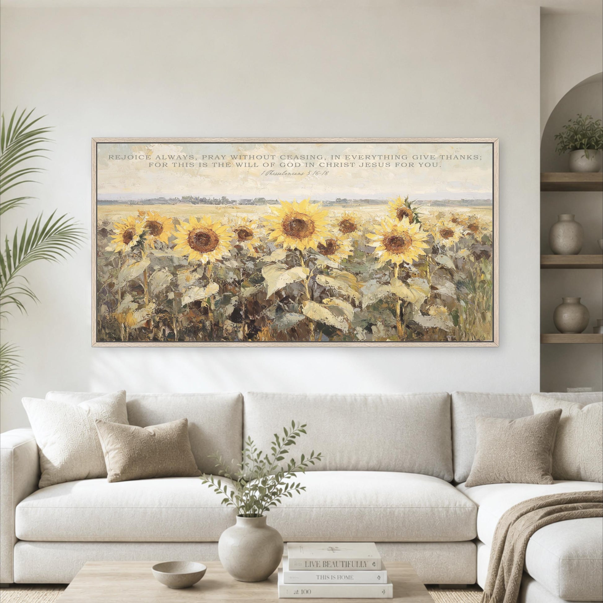 a large painting of a field of sunflowers hanging on a wall above a white sofa in a living room.