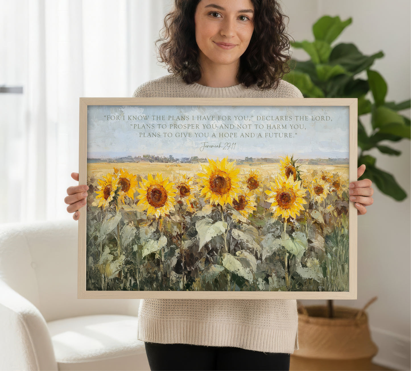A woman is holding a framed painting of a field of sunflowers in front of her.