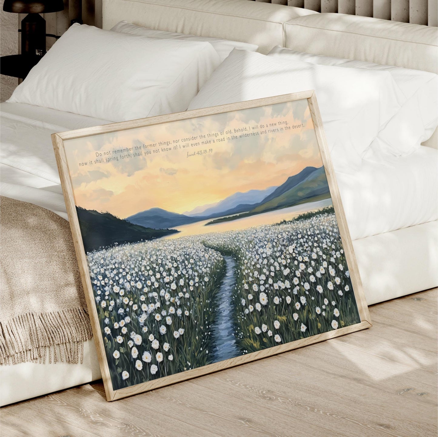 a framed painting of a field of white flowers with a winding path leading through it, set against a backdrop of mountains and a sunset sky.