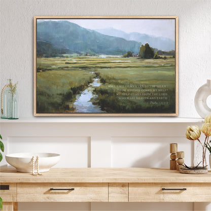 a framed painting of a serene landscape with a winding stream, set against a backdrop of mountains. The painting is hung on a white wall above a wooden shelf, which displays various decorative items such as a vase, a bowl, and a potted plant. The overall scene conveys a sense of tranquility and natural beauty.