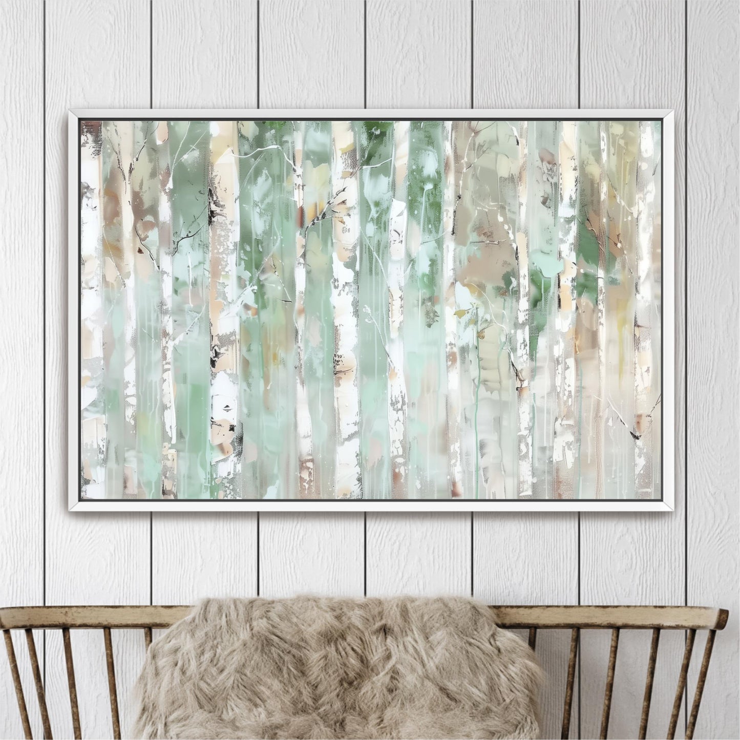 a large, framed painting of a forest scene with tall trees and a mix of green and white colors. The painting is hanging on a white wall above a wooden chair.