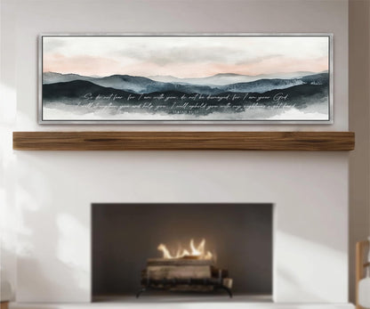 a fireplace with a warm fire burning inside, and above it is a framed painting depicting a serene landscape with mountains and a cloudy sky.