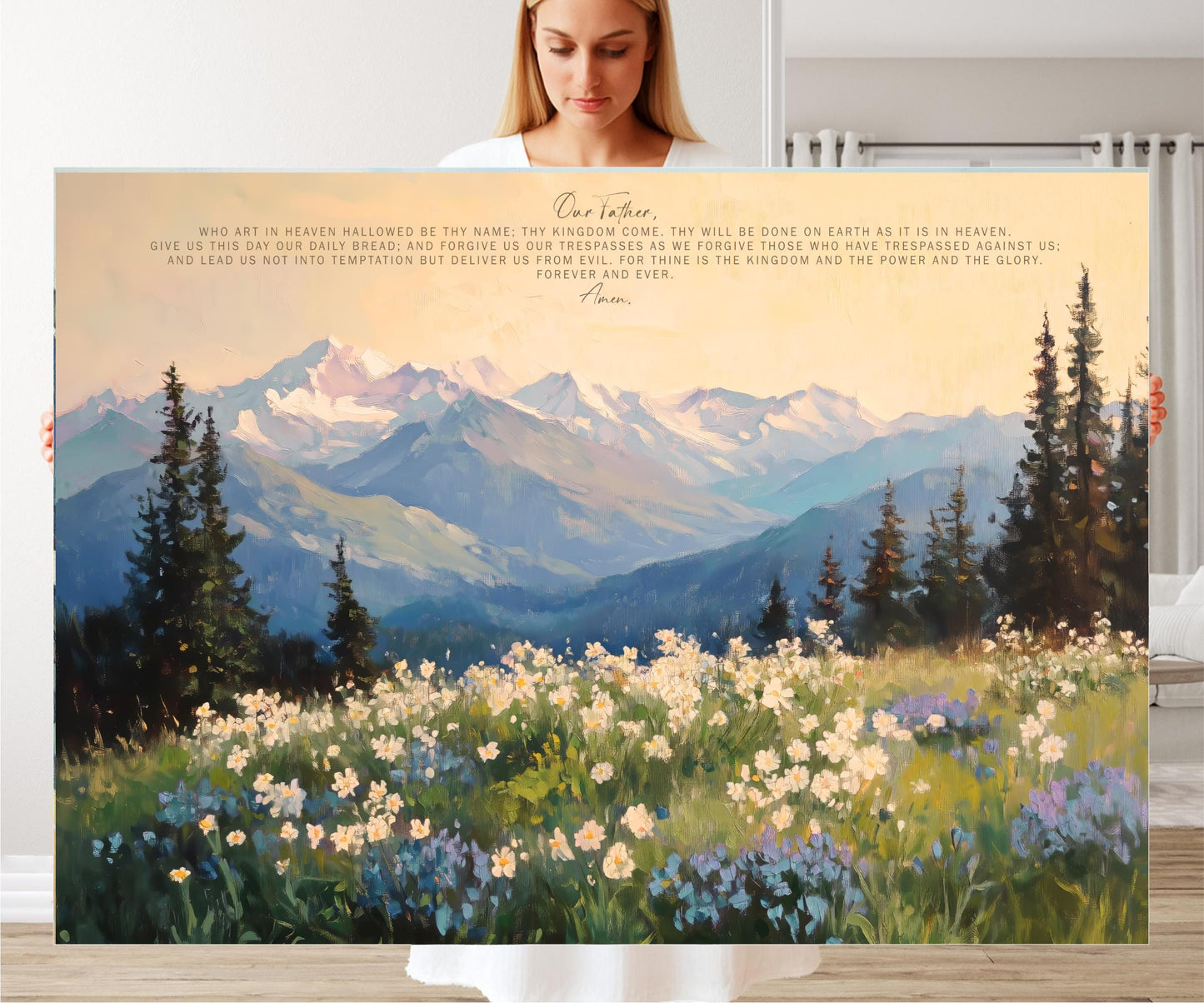 A woman is holding a large canvas print of a mountainous landscape with a field of flowers in the foreground.