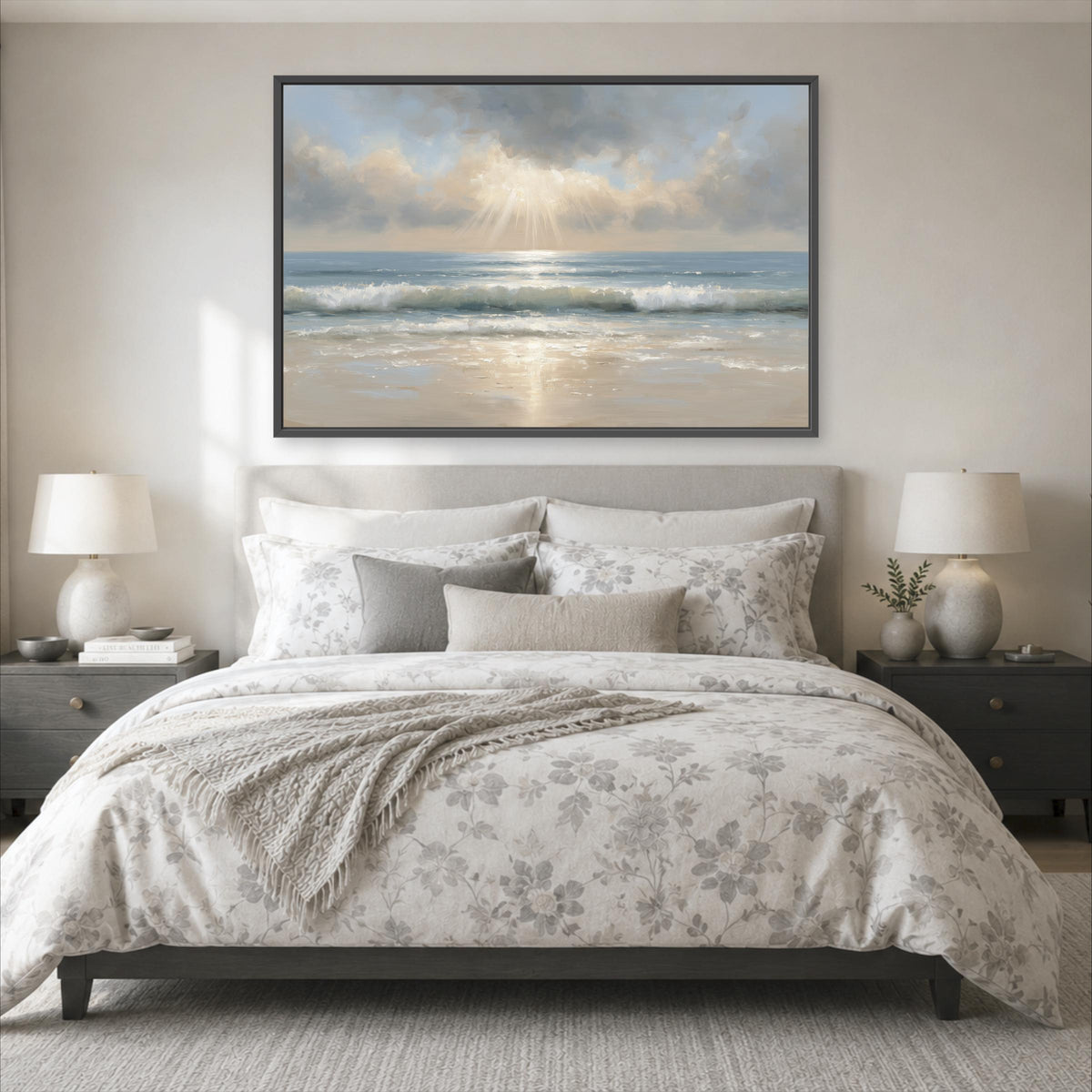 a serene bedroom scene with a large bed adorned with a floral comforter and pillows, flanked by two nightstands with lamps. Above the bed, a large painting of a beach scene with a cloudy sky and sunbeams is displayed on the wall.