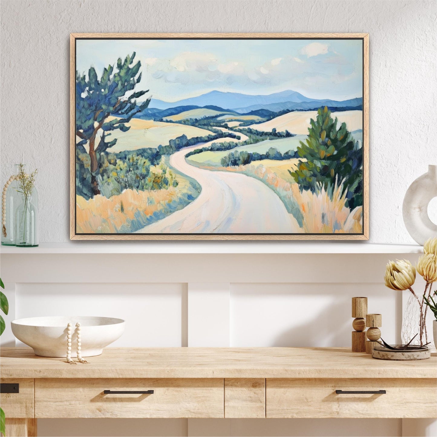 a large landscape painting hanging on a wall above a wooden table with various decorative items on it.
