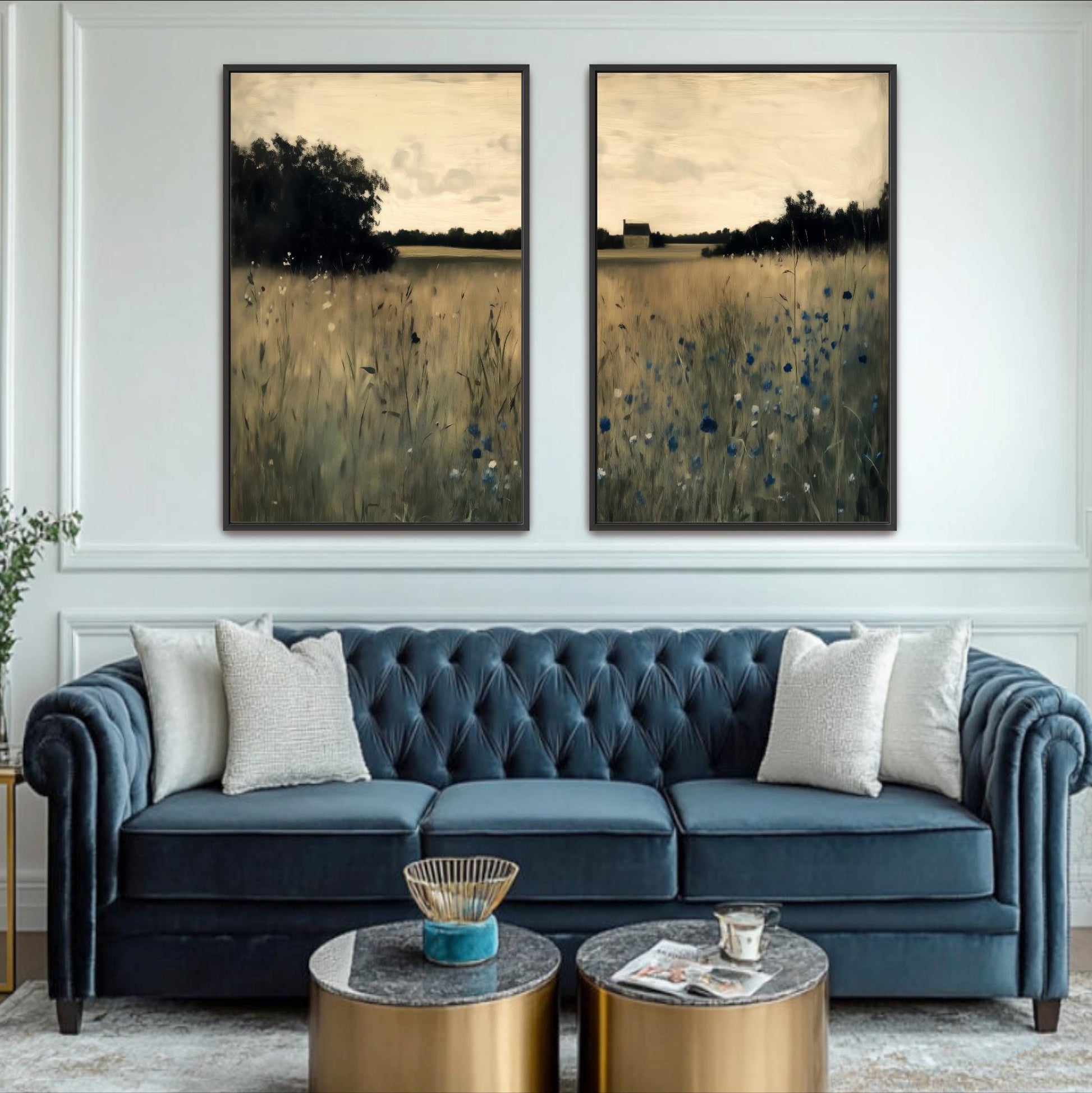 a living room with a blue tufted sofa, two framed landscape paintings on the wall, and a coffee table in front of the sofa.