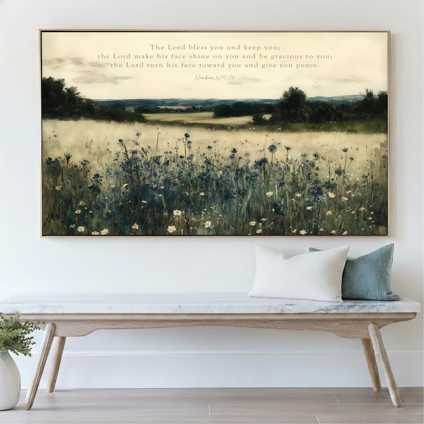 a large painting of a field with flowers hanging on a wall above a wooden bench with pillows.