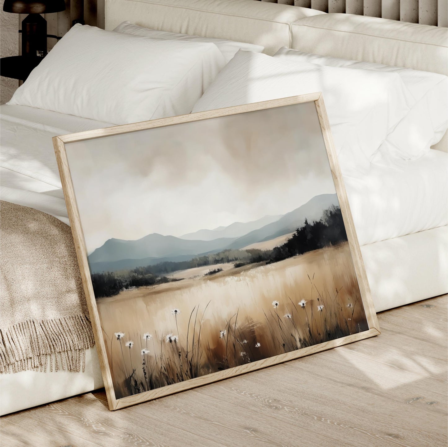 a framed painting of a field with tall grass and wildflowers, set against a mountainous landscape.