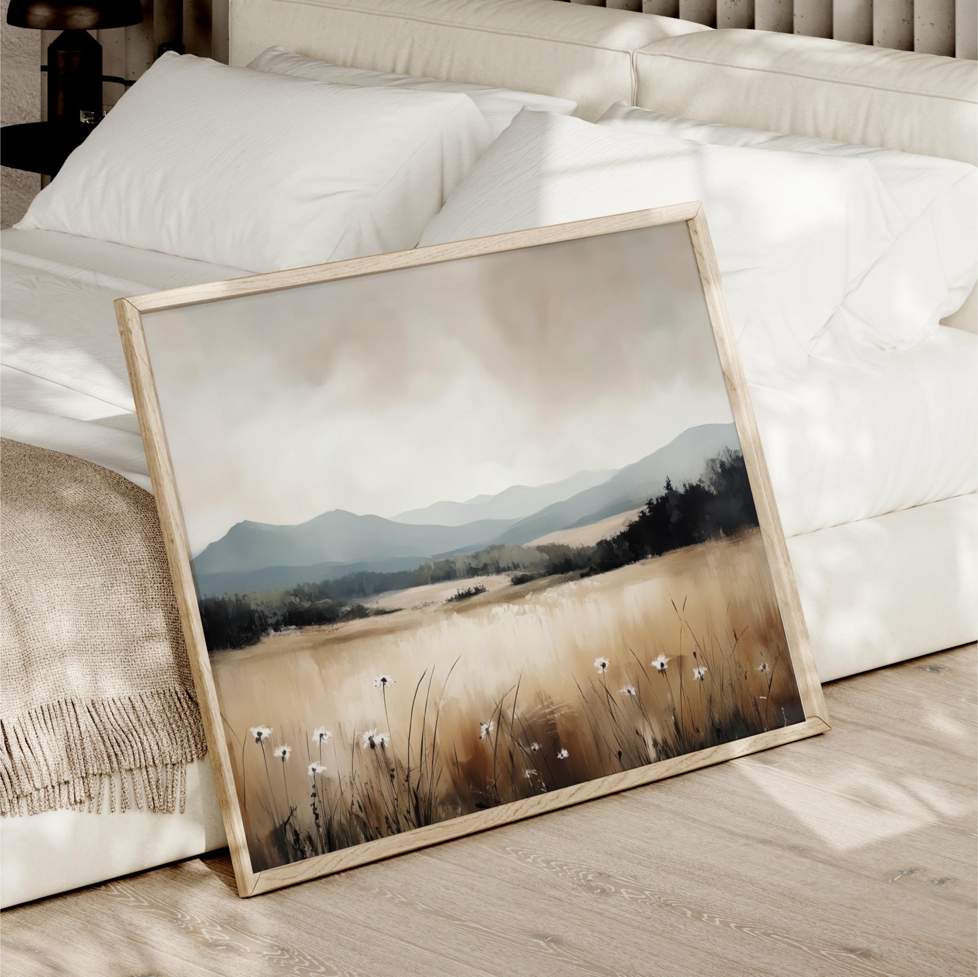 a framed painting of a field with tall grass and wildflowers, set against a mountainous landscape.