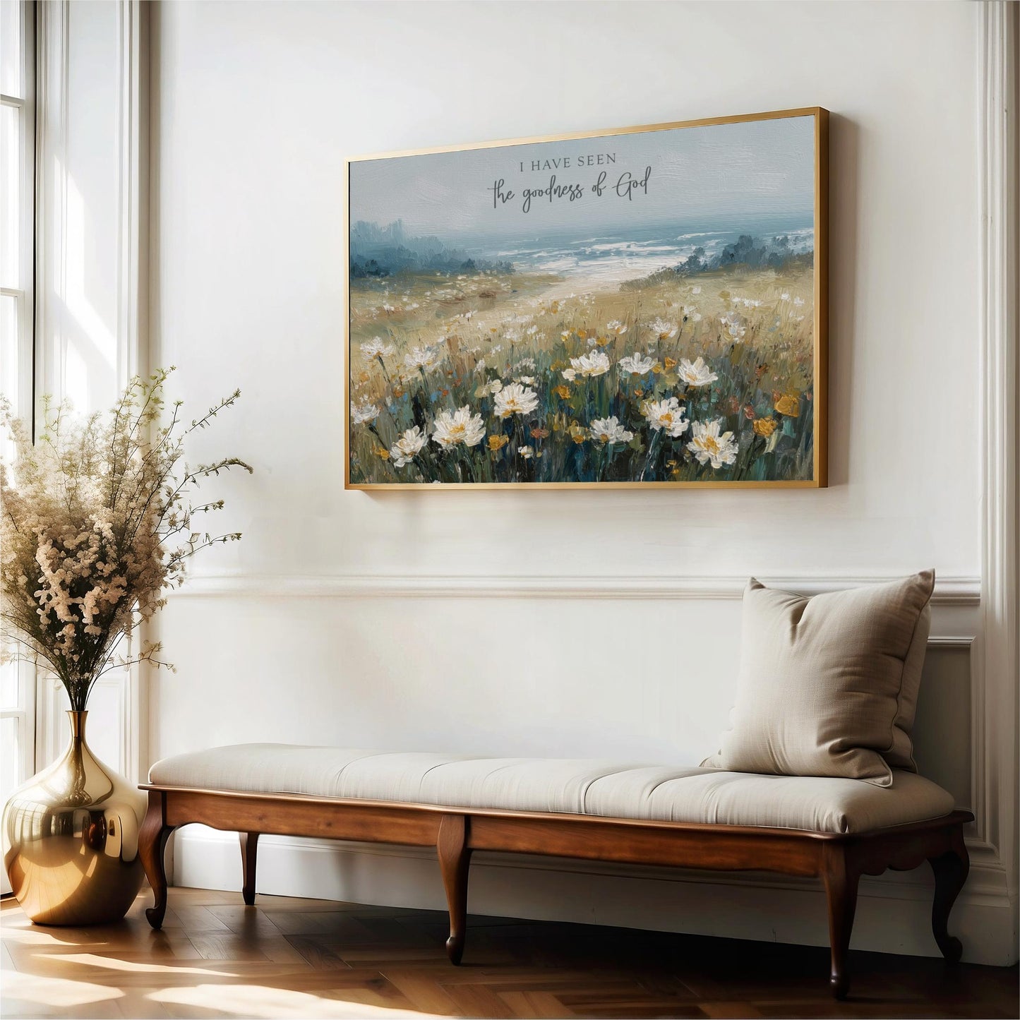 a large painting of a field of flowers hanging on a white wall, with a wooden bench and a vase of flowers placed next to it.
