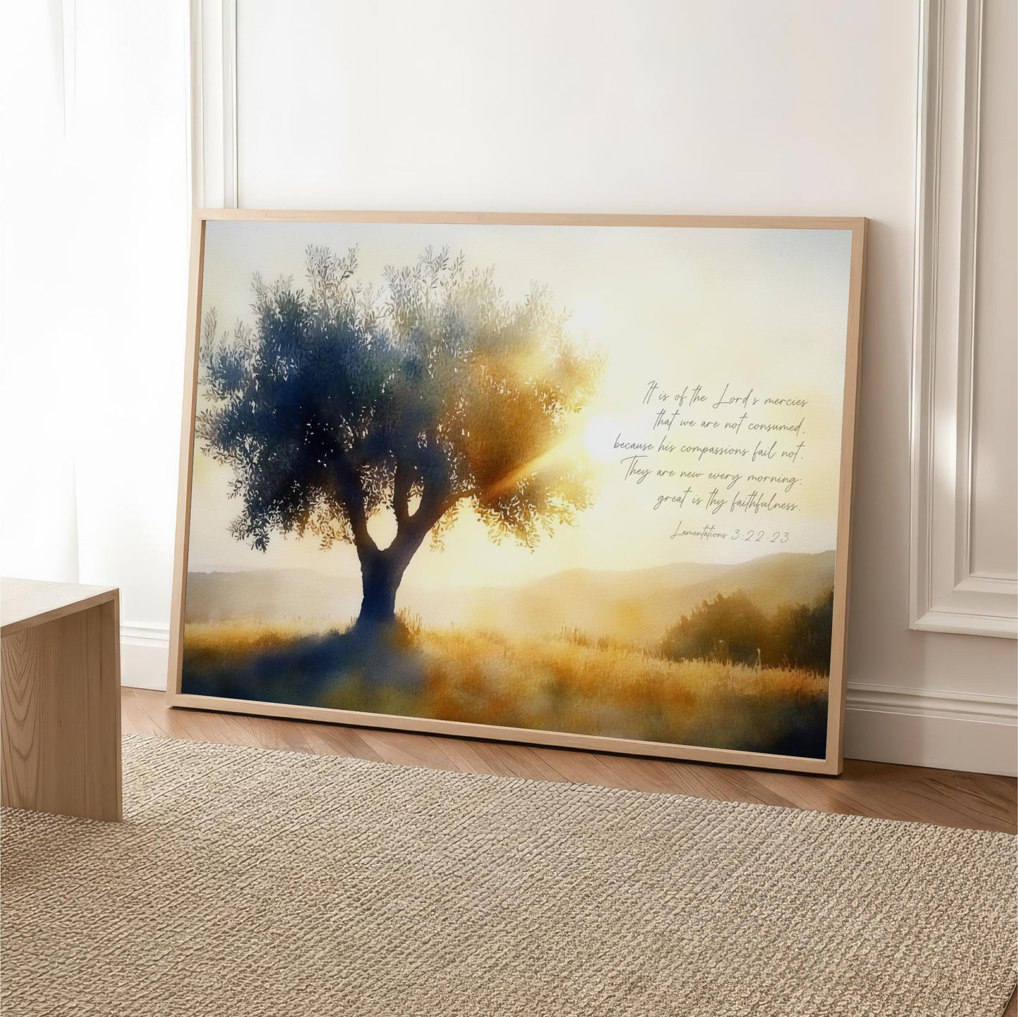The image is a framed painting depicting a serene landscape with a large tree in the foreground and a golden field in the background, bathed in warm sunlight. The painting is hung on a wall, and there is a text overlay that reads "It is of the Lord's mercy that we are not consumed because they are repressed, and they are now very good news. They are now very good news."