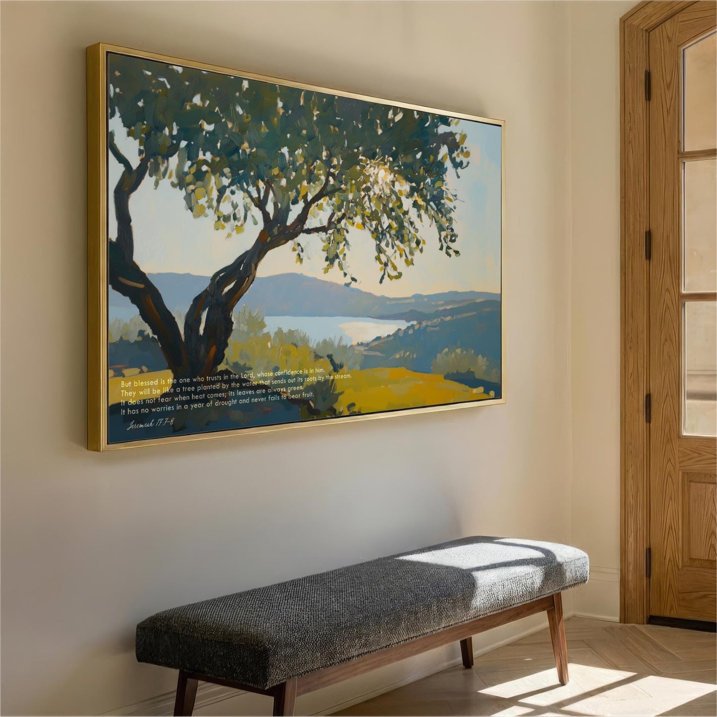 a large painting of a tree with a blue sky and green hills in the background, hanging on a wall above a gray bench.