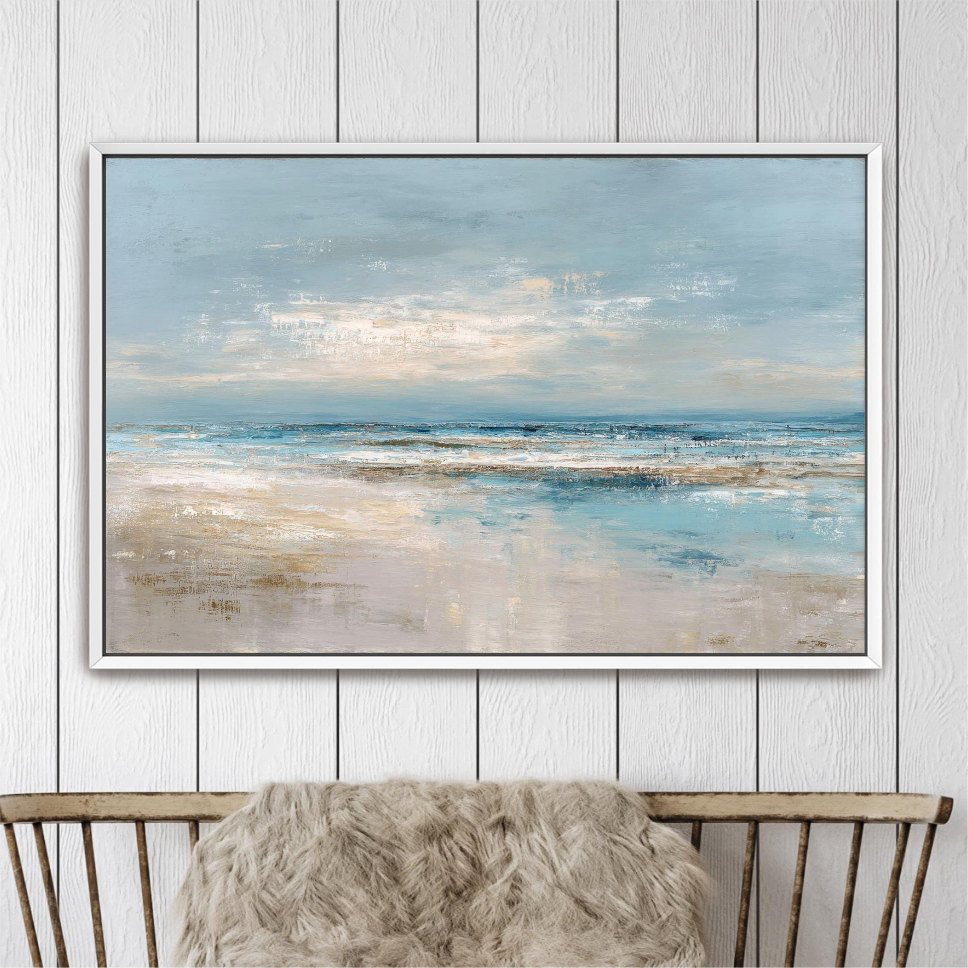 a large, framed painting of a serene beach scene with a blue sky, ocean, and sandy beach.
