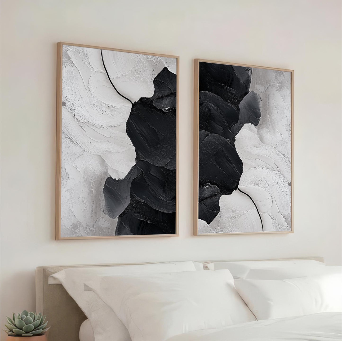 two large black and white abstract paintings hanging on a wall above a bed with white pillows.