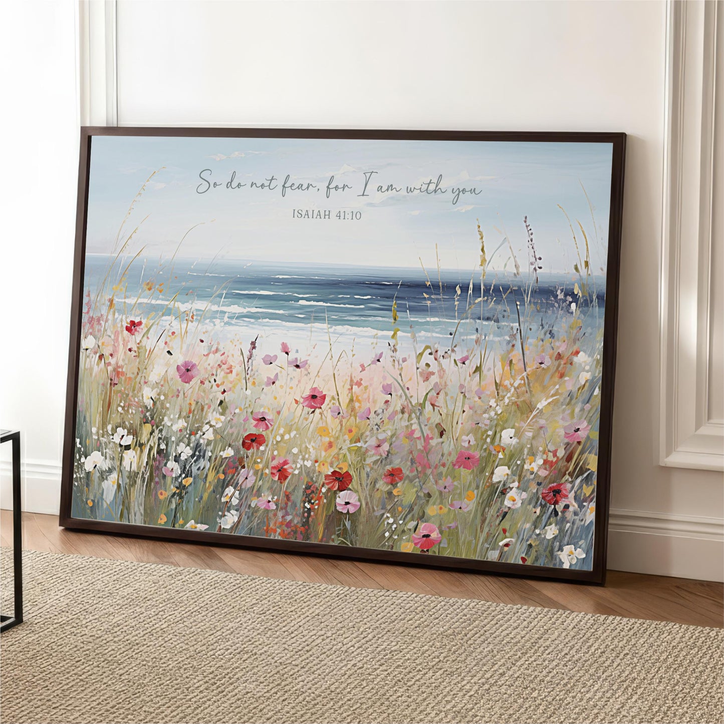 A framed painting depicting a field of colorful wildflowers with a body of water in the background, accompanied by a Bible verse.
