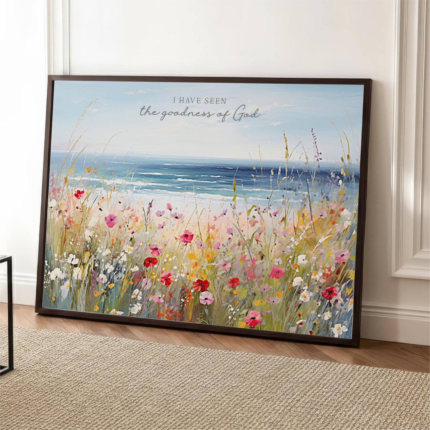The image is a framed painting depicting a vibrant field of flowers with a serene body of water in the background.