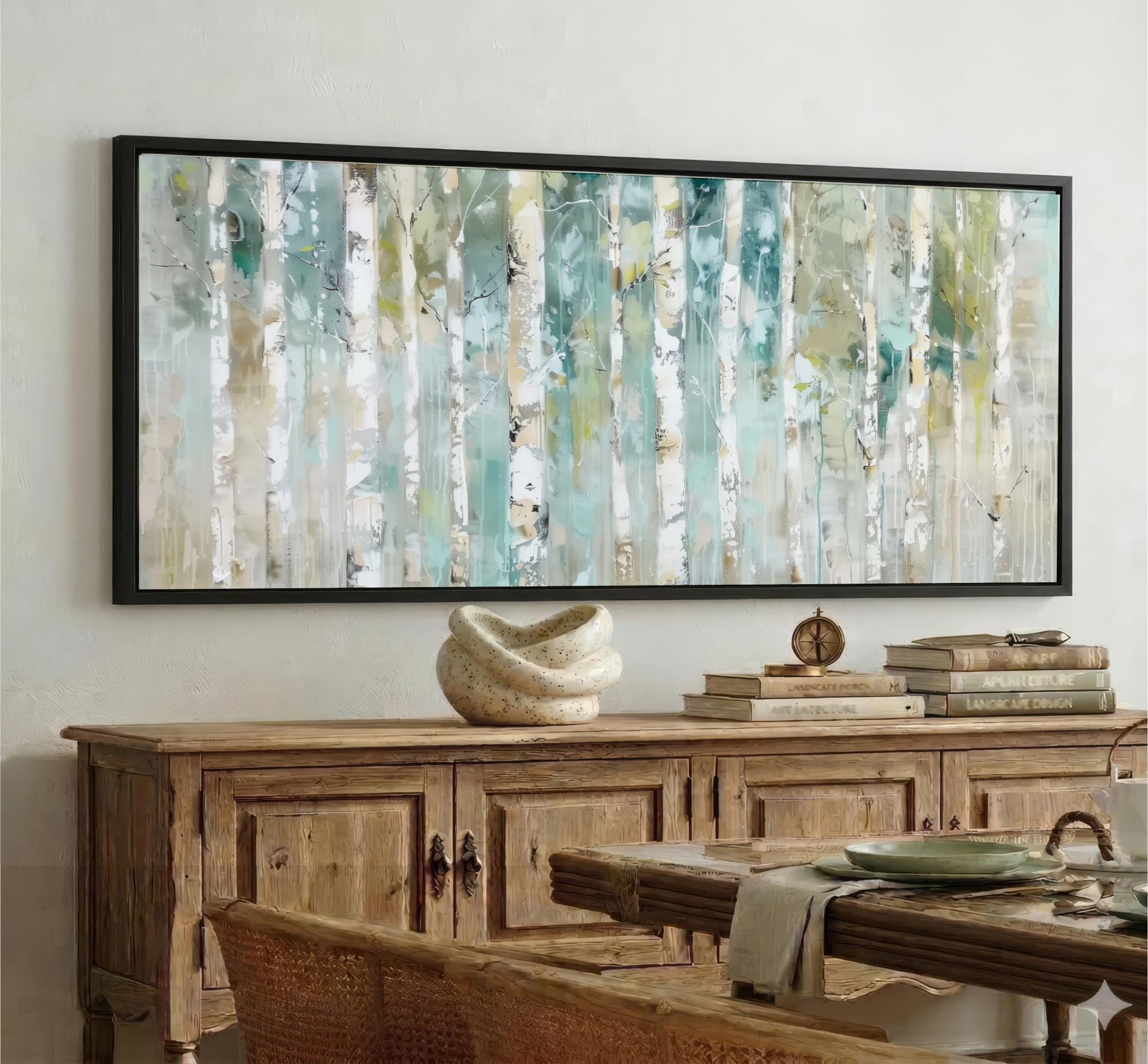 a large, abstract painting of trees with a mix of green, blue, and white colors, hanging on a wall above a wooden cabinet. The cabinet has a wicker top and is filled with various items, including books and a decorative vase. The overall scene appears to be a cozy and well-decorated living space.