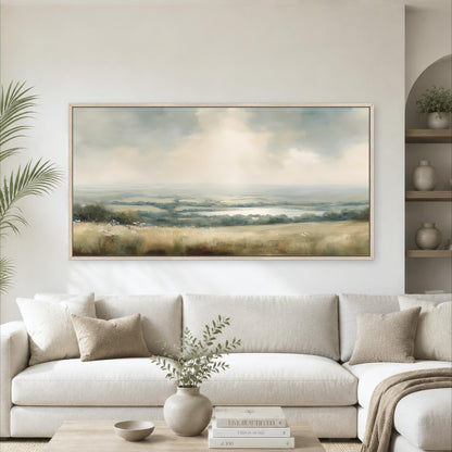 a large landscape painting hanging on a wall above a white sofa in a living room setting.