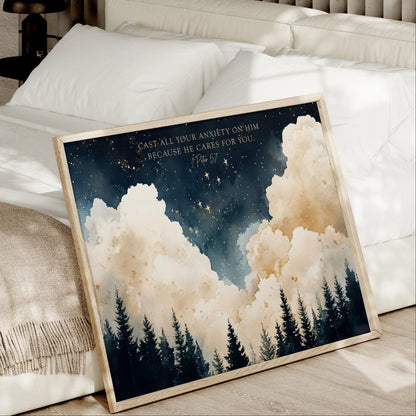 a framed painting of a night sky with clouds and trees, placed on a bed.