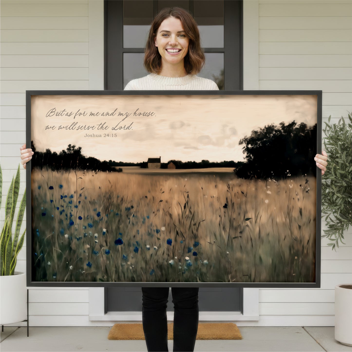 A woman is holding up a large framed print of a pastoral landscape with a text overlay that reads "But as for me and my house we will serve the Lord".