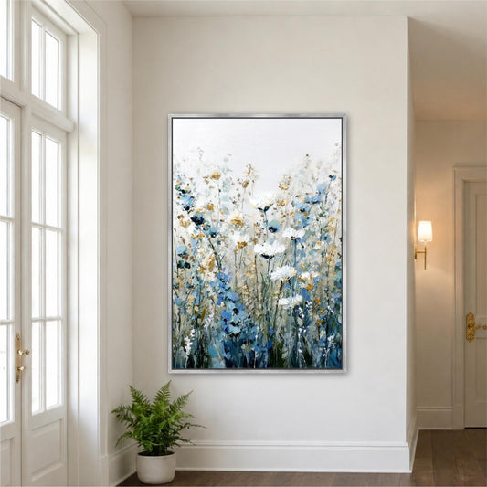 a large framed painting of flowers hanging on a white wall in a room with a window and a plant.