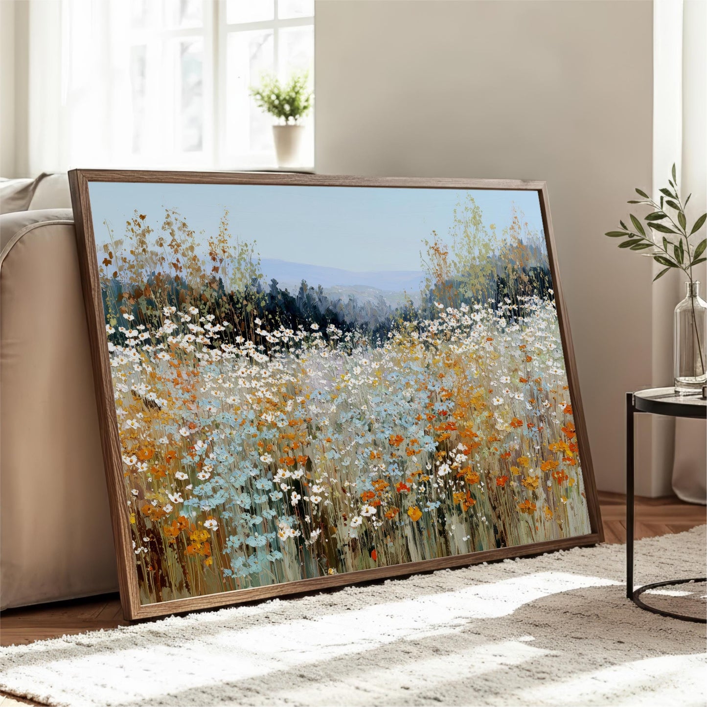 a large framed painting of a field of flowers, with a mix of blue, orange, and white colors, displayed on a wooden stand in a living room.