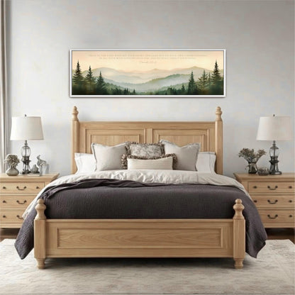 a serene bedroom setting with a large wooden bed, a wooden headboard, and a framed landscape painting above it. The painting depicts a forest scene with mountains in the background. The room has a neutral color scheme with a gray rug and white walls, creating a calm and peaceful atmosphere.