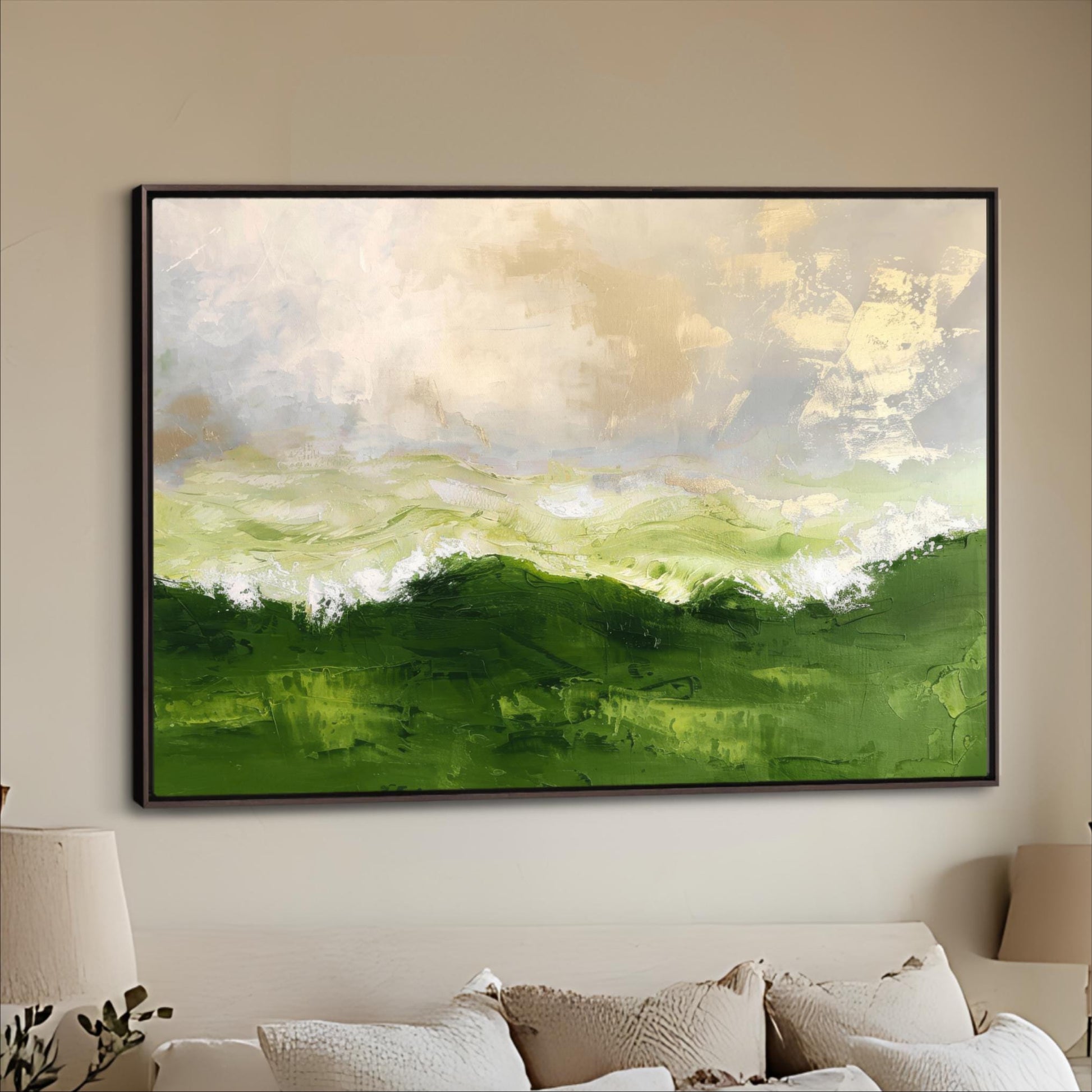 a large, framed painting of a landscape with green hills and a cloudy sky hanging on a wall above a couch.