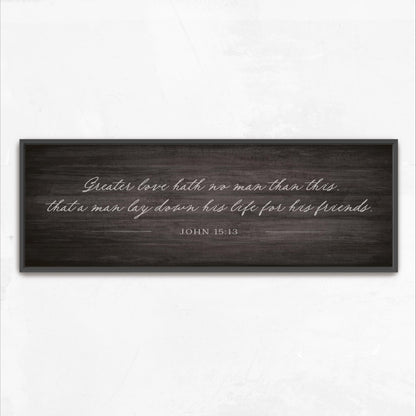 a black and white photograph of a wooden sign with a quote from the Bible verse John 15:13.